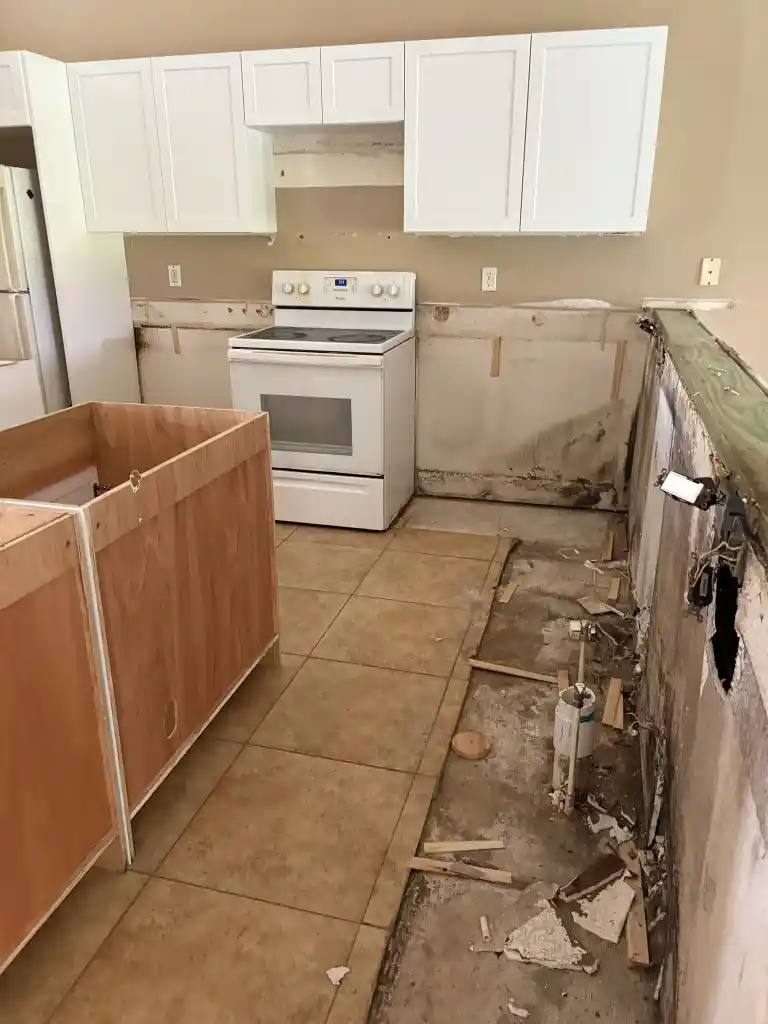 Kitchen with mold damage behind cabinets and water-damaged drywall before professional remediation