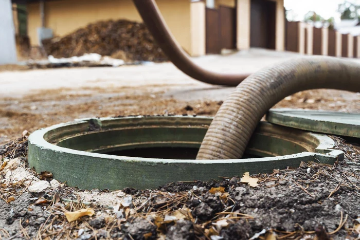 Professional hose extracting water from sewer access point representing contamination risks